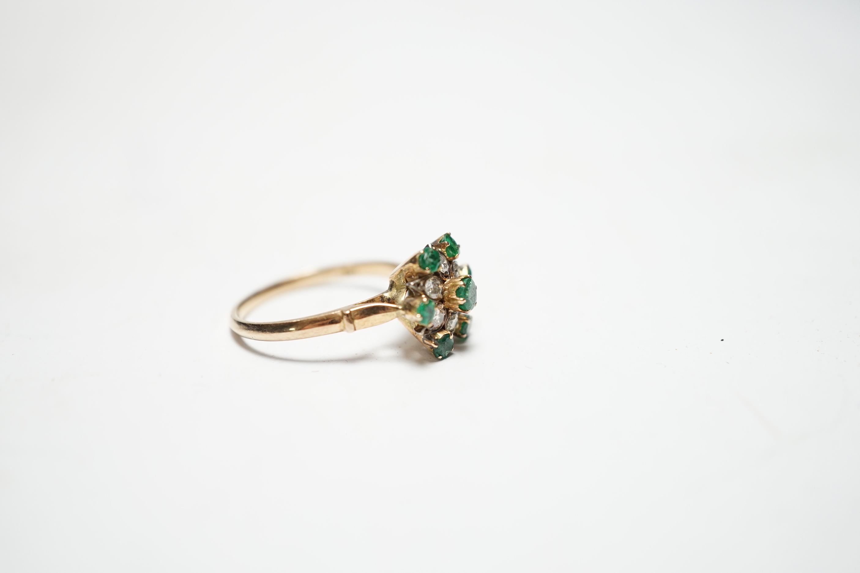 A 14ct, emerald and diamond set flowerhead cluster ring, size N/O, gross weight 3.2 grams.